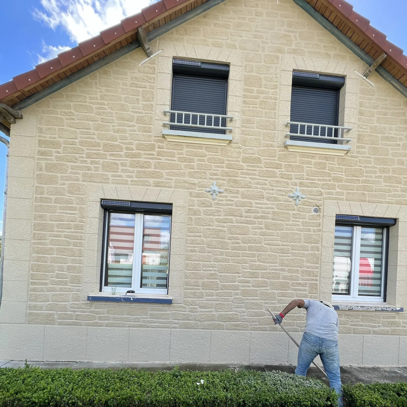 Artisan appliquant un enduit imitation pierre sur une façade