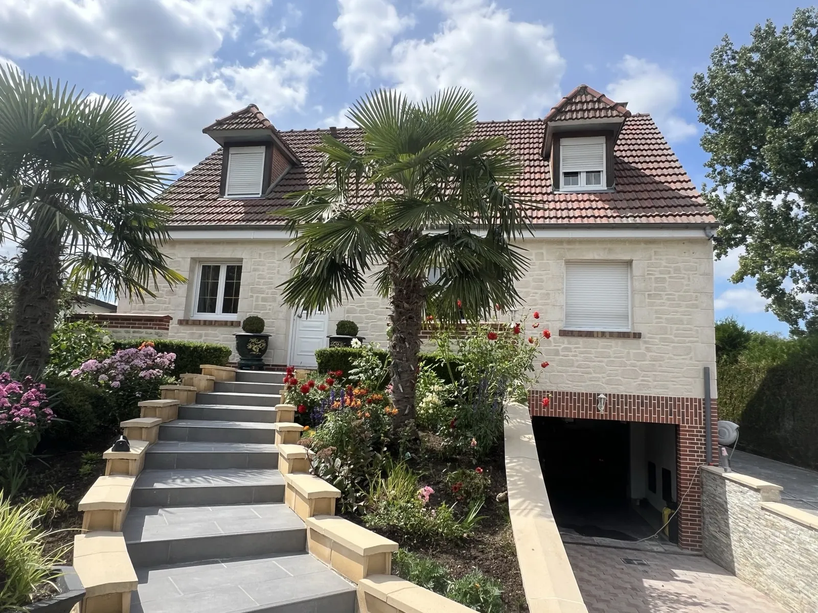 Maison en imitation pierre avec escalier d'accès et jardin