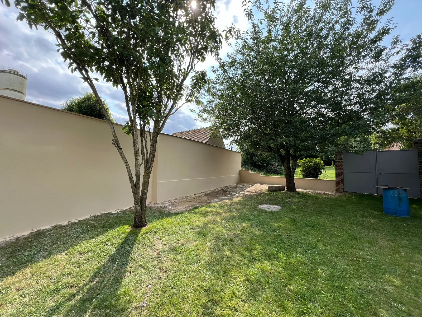 Mur de clôture enduit en blanc dans un jardin