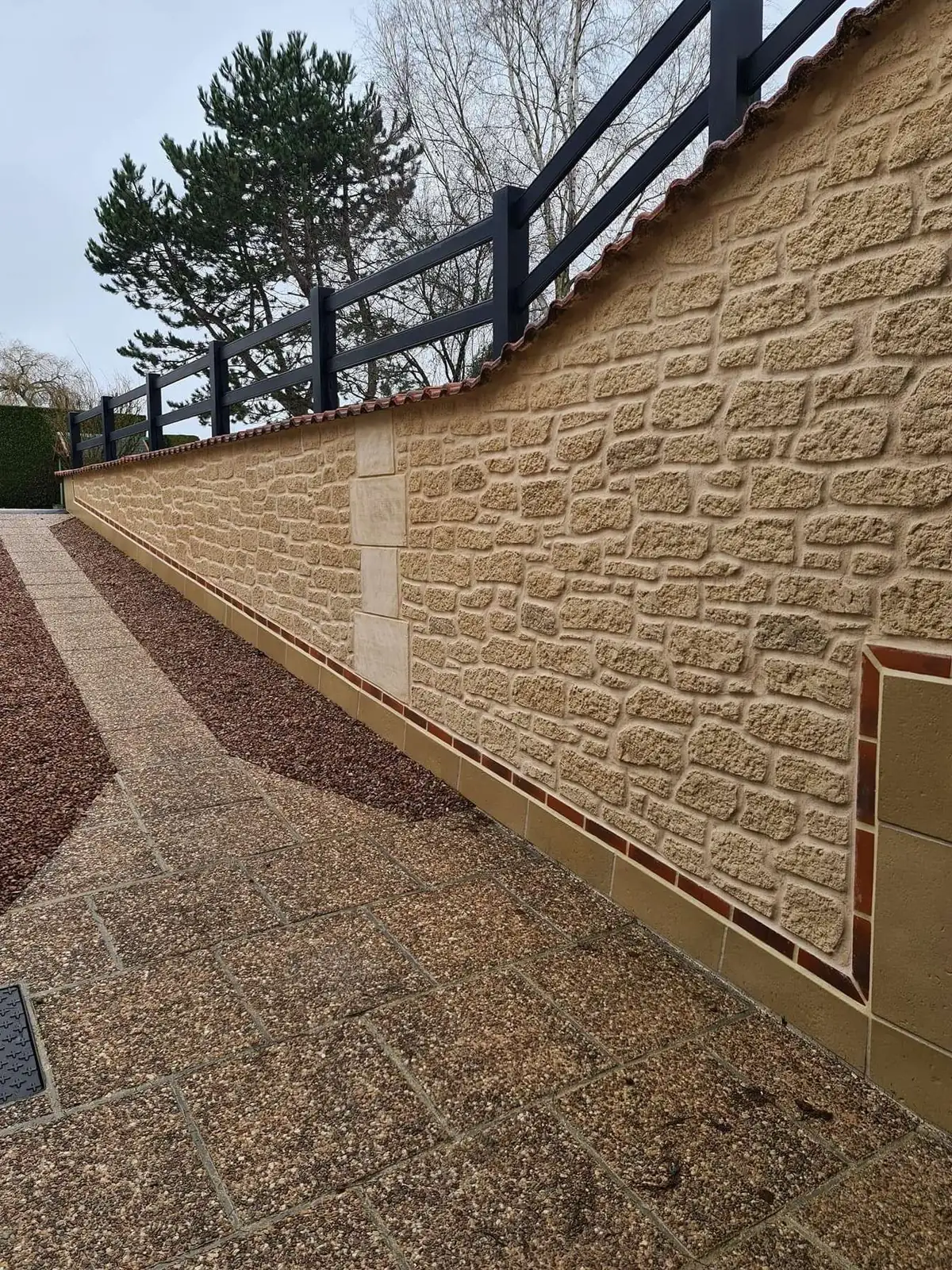 Mur de soutènement en imitation pierre le long d'une allée