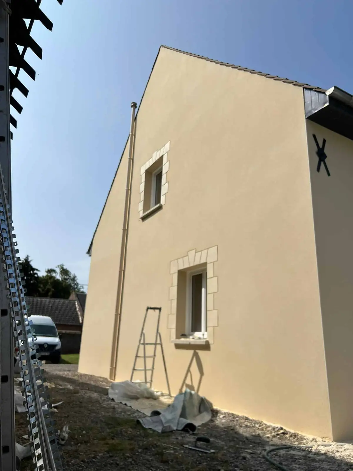 Chantier de ravalement de façade avec échafaudage sur une maison en enduit crème